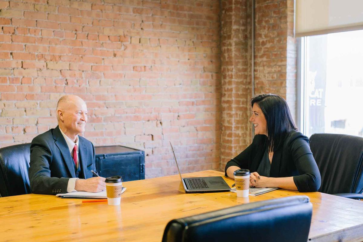 Man and woman sitting at a desk in a meeting room while practising different feedback techniques