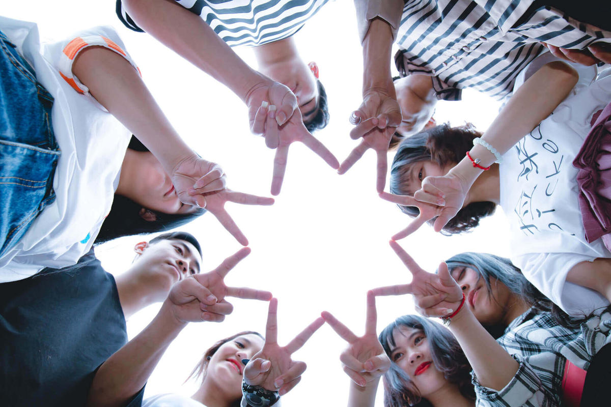 young team members putting their peace-sign-making fingers together showing a star,