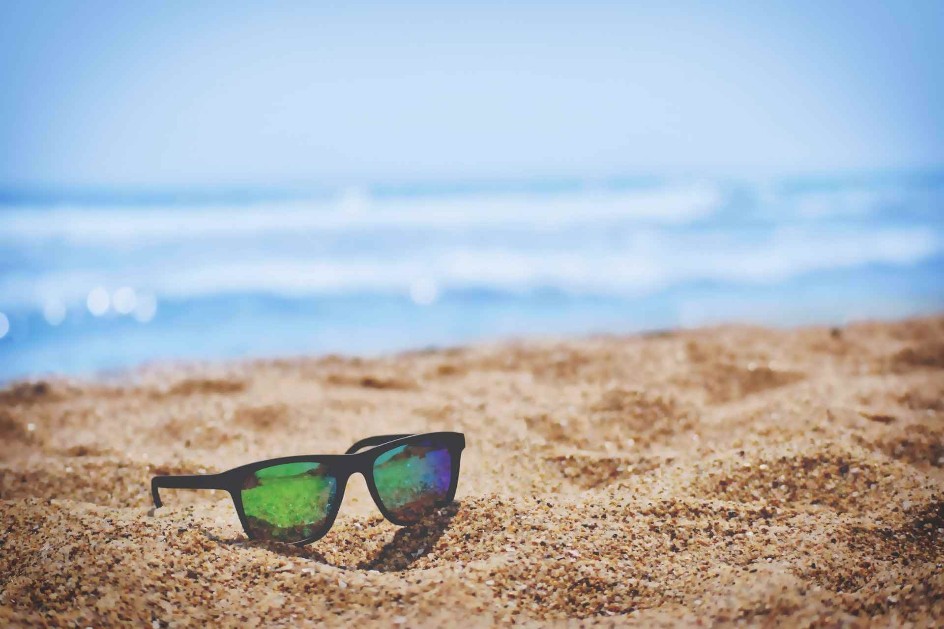 Pair of sunglasses on a beach illustrating a way to celebrate Employee Appreciation Day with extra time off