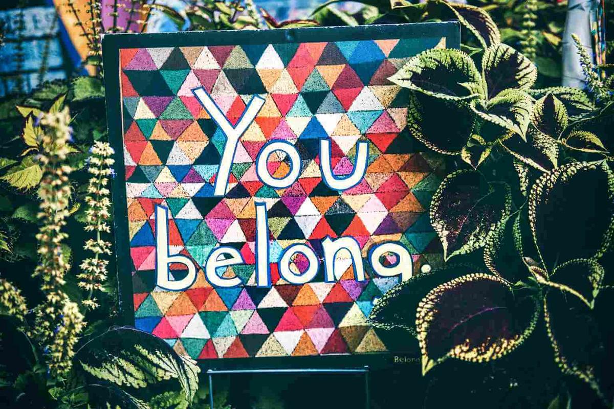 Colourful sign saying “you belong”, referring to someone being a culture fit, with plants in the background