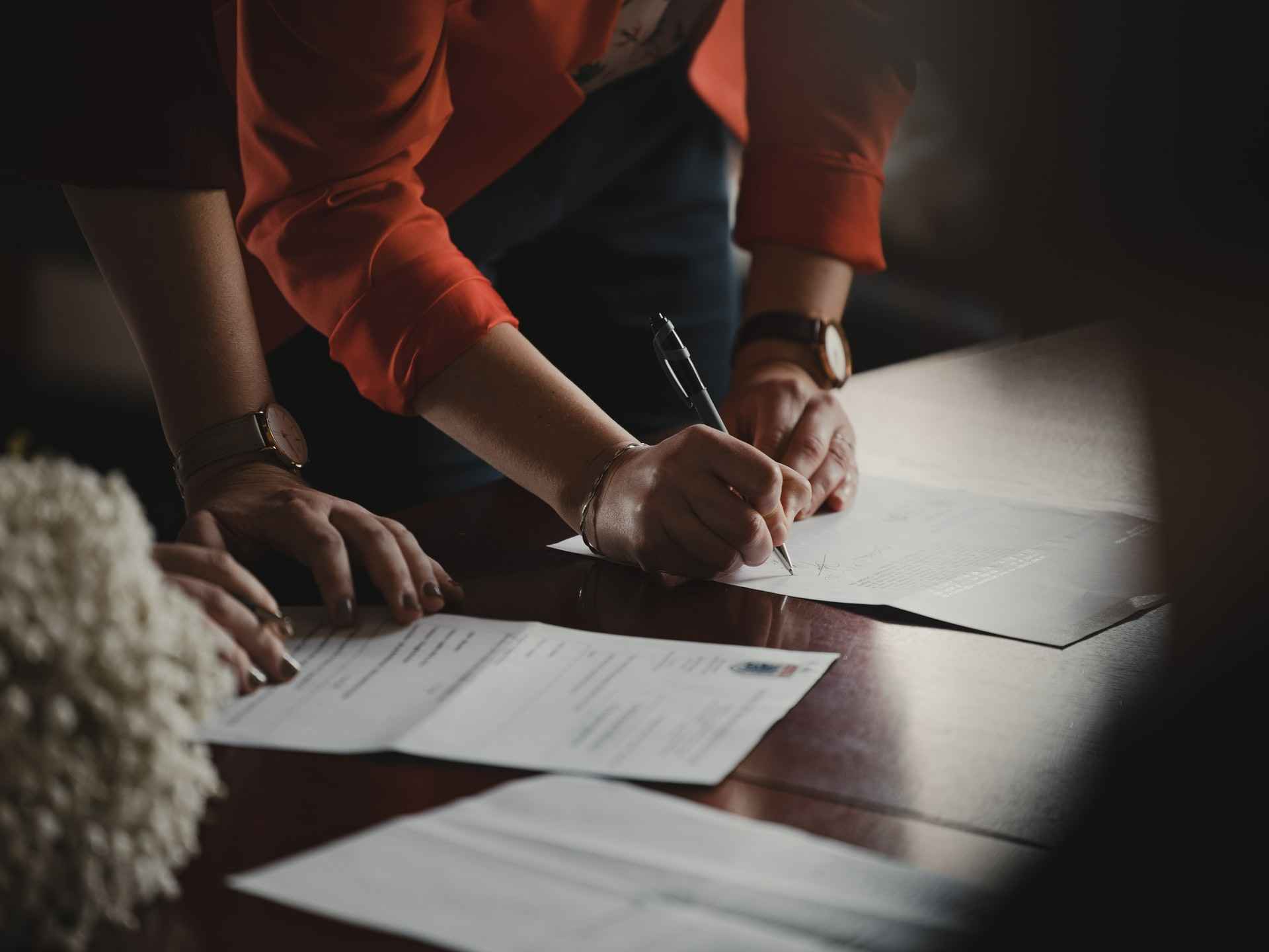 Two women at a desk signing contracts to represent rehiring employees