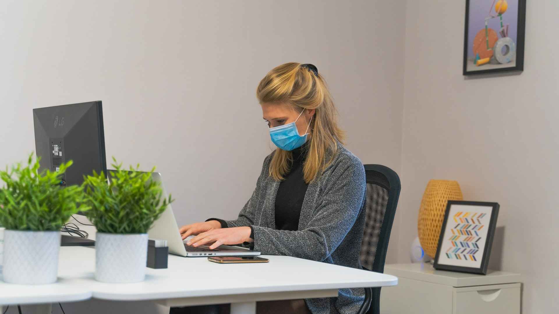 Employee at an office desk wearing a face mask to ensure it’s safe to go back to the office