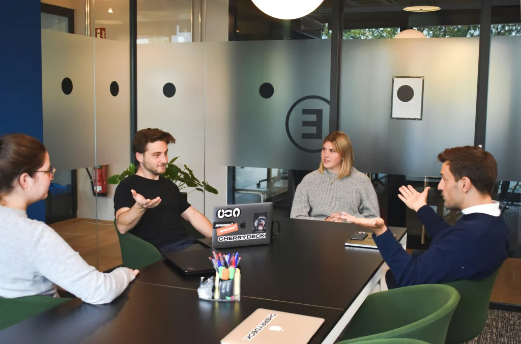 Teammeeting rund um einen Tisch, bei dem Ideen diskutiert werden – kollaboratives Recruiting in der Praxis.